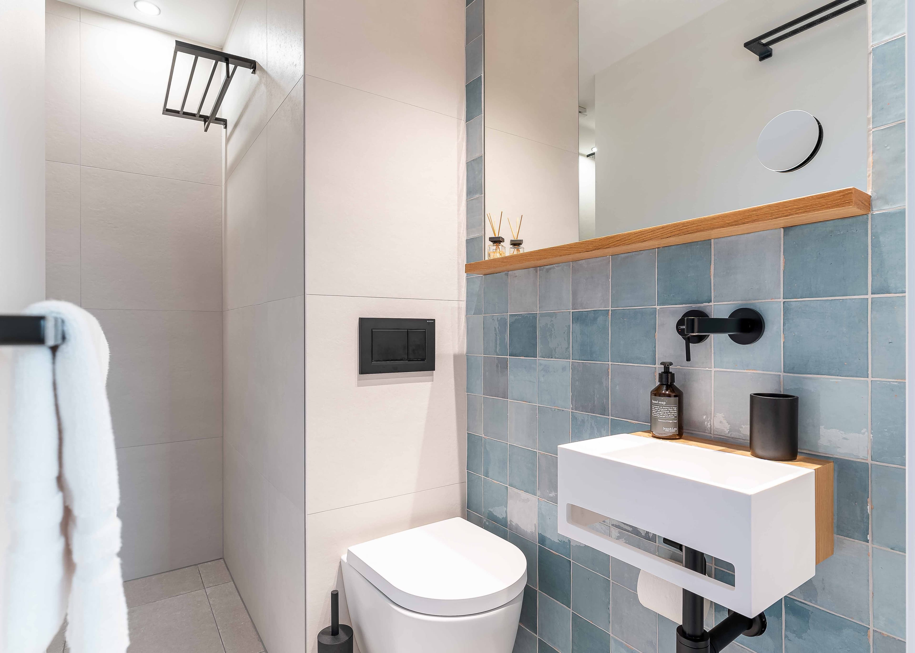 Walk-in-Regendusche im Gästebad mit Kneippflasche und azur-blauer Zellige-Akzentwand