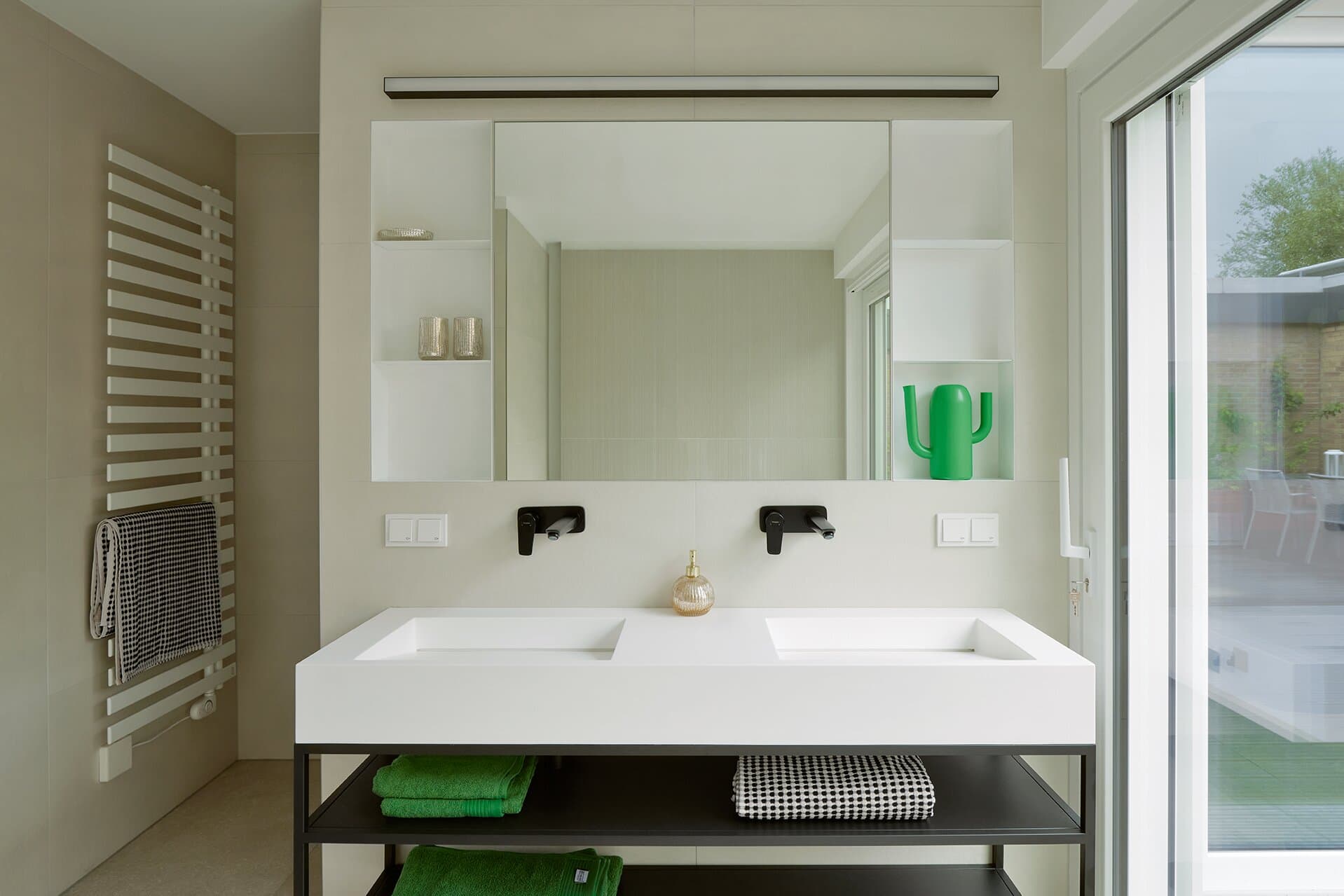 Doppelwaschbecken im Masterbad mit zwei schwarzen Wand-Armaturen, großem Spiegel und Handtuchheizkörper