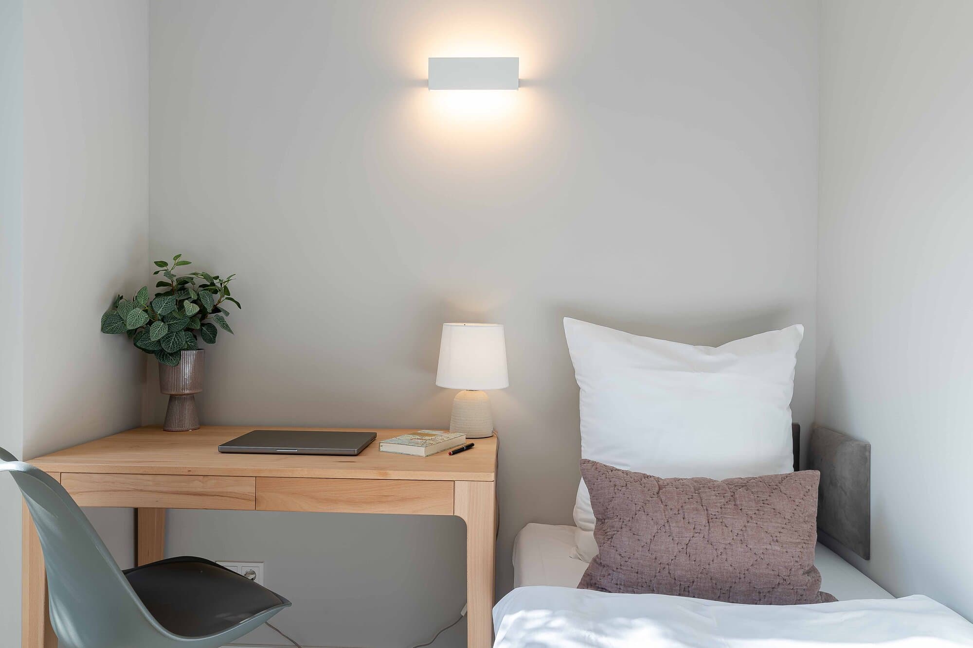 Schreibtisch mit Laptop, Lampe und Pflanze im dritten Schlafzimmer, ruhige Arbeitsecke