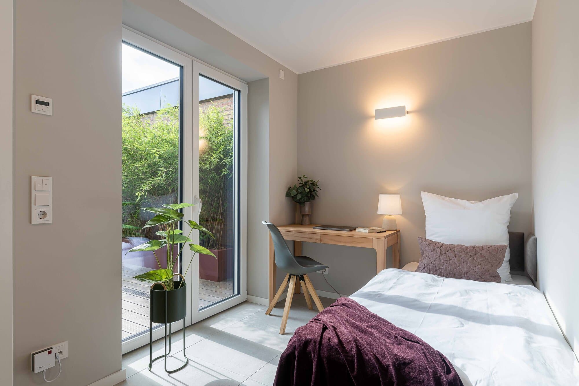 Arbeitsplatz und Schlafzimmer in einem, Bungalow Ratingen, drittes Zimmer mit Eichen-Schreibtisch und bodentiefem Fenster zur Bambus-Terrasse