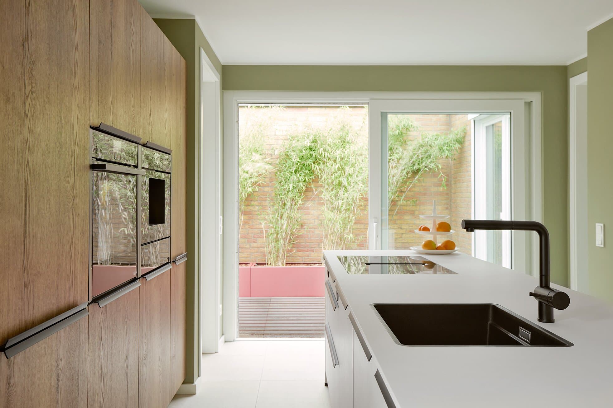 Premium-Küche mit Eichen-Hochschrankzeile, weißer Kücheninsel, Induktionskochfeld und Blick auf die Bambus-Terrasse