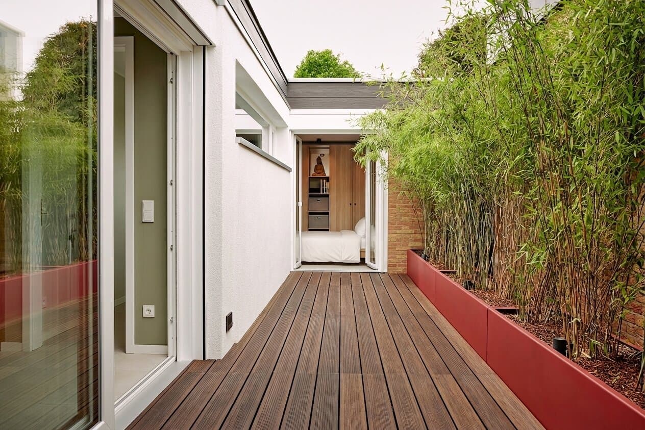 Bambus-Hof als schmaler Korridor entlang der weißen Außenwand, am Ende offene Tür zum Master-Schlafzimmer